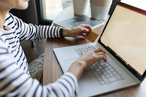 Nahaufnahme einer Frau, die einen Laptop zum Online-Shopping zu Hause benutzt, lizenzfreies Stockfoto