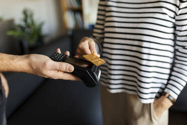 Nahaufnahme einer Frau, die zu Hause mit einer Kreditkarte bezahlt - VABF02417
