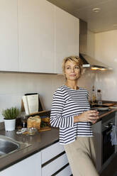 Mature woman relaxing in kitchen at home - VABF02431