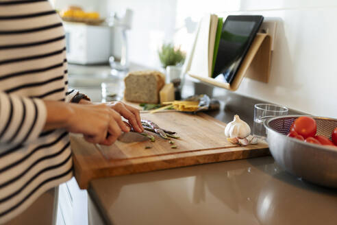 Close-up of woman cooking in kitchen at home cutting vegetables - VABF02432