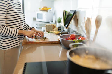Nahaufnahme einer Frau, die in der Küche zu Hause Gemüse schneidet - VABF02433