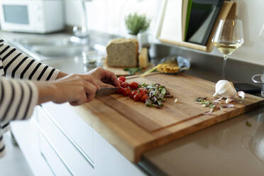 Close-up of woman cooking in kitchen at home cutting vegetables - VABF02440