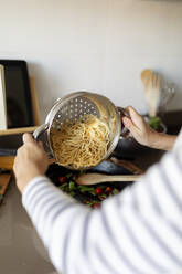 Close-up of woman cooking pasta dish in kitchen at home - VABF02443