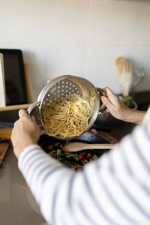 Nahaufnahme einer Frau beim Kochen eines Nudelgerichts in der Küche zu Hause - VABF02443