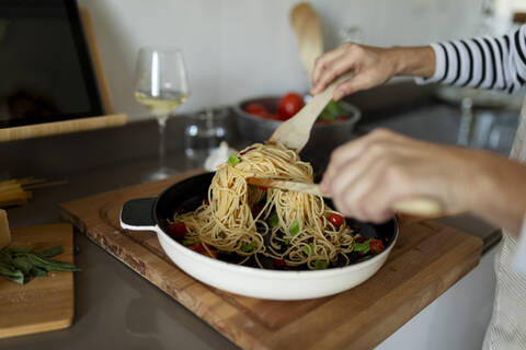 Close-up of woman cooking pasta dish in kitchen at home stock photo