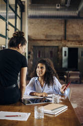 Two young businesswomen with smartphone in loft office - SODF00366