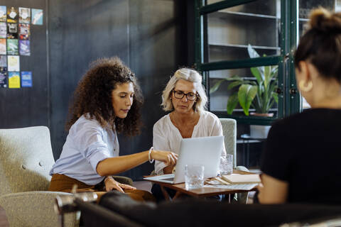 Geschäftsfrauen mit Laptop arbeiten zusammen in einem Loftbüro, lizenzfreies Stockfoto
