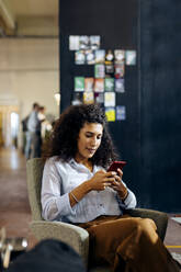 Junge Geschäftsfrau mit Smartphone im Loftbüro - SODF00373