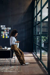 Young businesswoman using smartphone in loft office - SODF00404