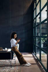 Young businesswoman using smartphone in loft office - SODF00405