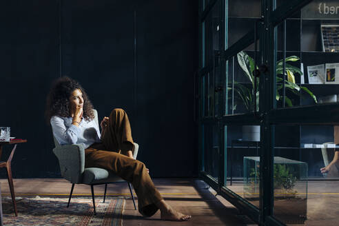 Young businesswoman looking out of window in loft office - SODF00412