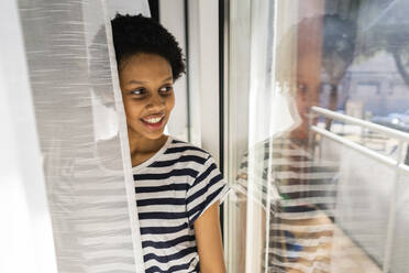 Junge Frau zu Hause mit Blick aus dem Fenster - GIOF07798