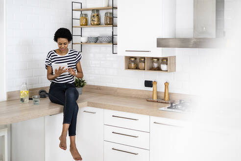 Young woman using tablet in kitchen at home - GIOF07808