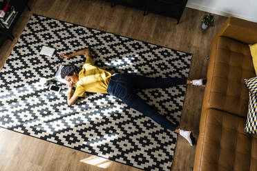 Young woman lying on the floor at home with closed eyes - GIOF07821