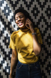 Happy young woman lying on carpet talking on the phone - GIOF07825