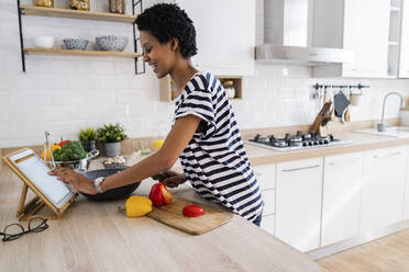 Young woman using tablet cooking in kitchen at home - GIOF07840