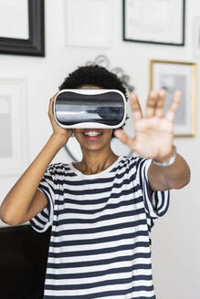 Junge Frau mit VR-Brille zu Hause - GIOF07860