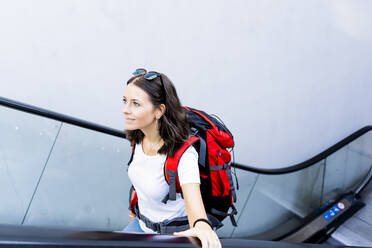 Junge Rucksacktouristin auf Rolltreppe, Verona, Italien - GIOF07866