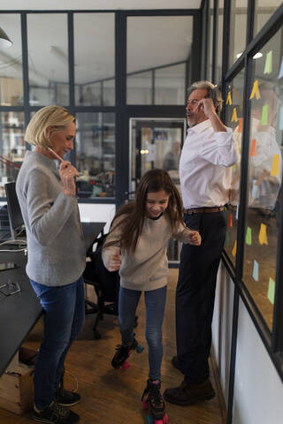 Businessman and businesswoman with girl on roller skates in office stock photo