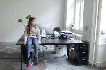 Girl with roller skates sitting on desk in office - GUSF02692