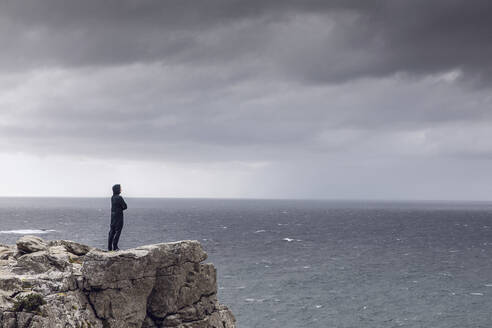 Mann steht auf einer felsigen Klippe und schaut auf den Horizont, Cape Point, Westkap, Südafrika - MCF00330