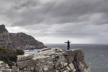 Mann steht auf einer felsigen Klippe und schaut auf den Horizont, Cape Point, Westkap, Südafrika - MCF00331