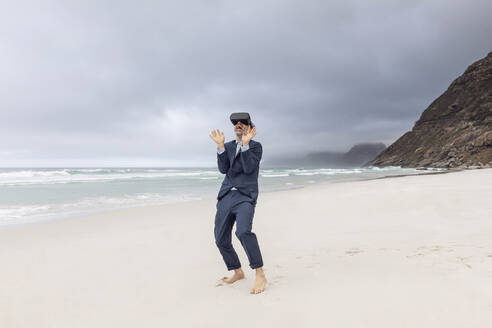 Geschäftsmann mit VR-Brille am Strand, Nordhoek, Westkap, Südafrika - MCF00352