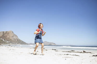 Girl with headphones singing and dancing on the beach, Cape Town, Western Cape, South Africa - MCF00363