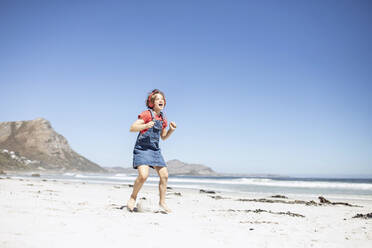 Mädchen mit Kopfhörern singt und tanzt am Strand, Kapstadt, Westkap, Südafrika - MCF00363