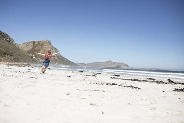 Girl listening music with headphones, dancing on the beach, Cape Town, Western Cape, South Africa - MCF00365