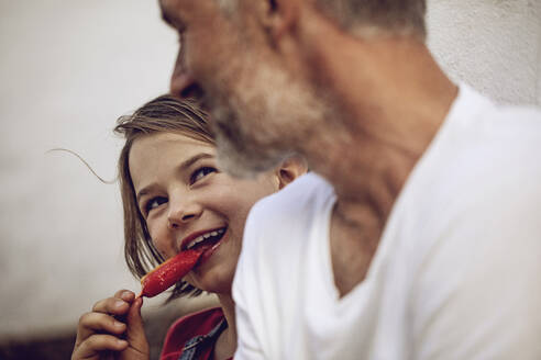 Portrait of smiling girl with popsicle looking at her father, Cape Town, Western Cape, South Africa - MCF00377