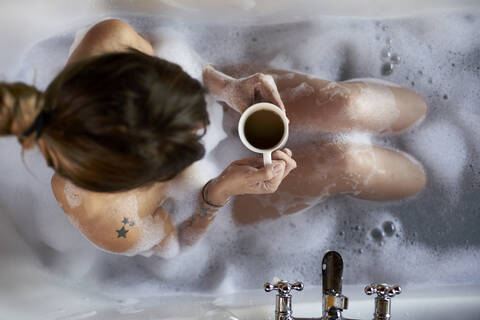 Woman having a relaxing bath and a cup of coffee in the bathtub stock photo