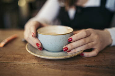 Nahaufnahme von Frauenhänden, die eine Kaffeetasse halten - MTBF00211