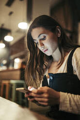 Frau benutzt ihr Smartphone in einem Café - MTBF00212