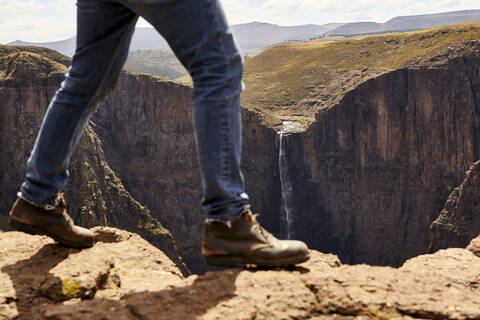 Tiefschnitt eines Mannes, der durch die Berge wandert, Maletsunyane Falls, Lesotho, lizenzfreies Stockfoto