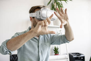 Portrait of man wearing VR glasses in office - VPIF01770