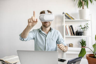 Man wearing VR glasses at desk in office - VPIF01771