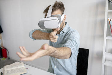 Man wearing VR glasses at desk in office - VPIF01773