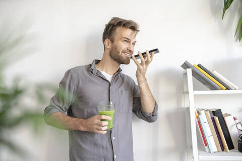 Lächelnder Mann mit Smartphone im Büro, lizenzfreies Stockfoto