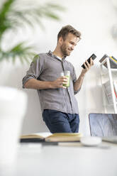 Smiling man using smartphone in office - VPIF01788