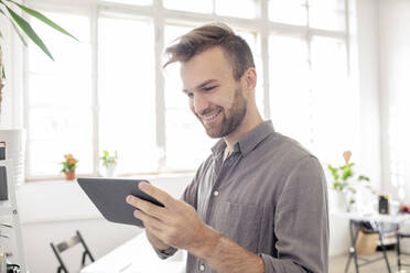 Smiling man using tablet in office - VPIF01789