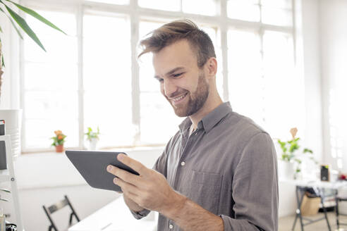 Lächelnder Mann mit Tablet im Büro - VPIF01789