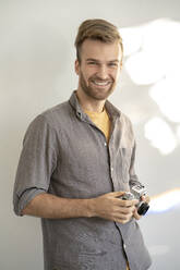 Porträt eines lächelnden Mannes, der eine altmodische Kamera hält - VPIF01811