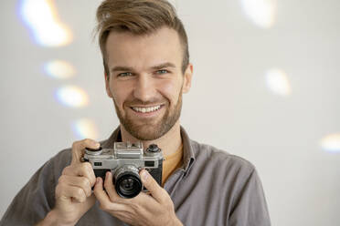 Porträt eines lächelnden Mannes, der eine altmodische Kamera hält - VPIF01814