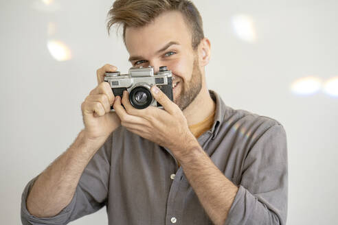 Portrait of smiling man taking picture with an old-fashioned camera - VPIF01815
