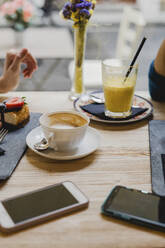 Cell phones, cake and drinks on table in a cafe - FMOF00753