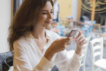 Portrait of young woman holding cell phone in a cafe - FMOF00756