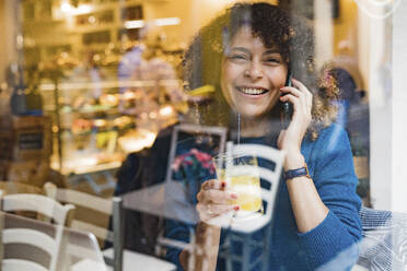 Porträt einer glücklichen Frau beim Telefonieren in einem Cafe - FMOF00767