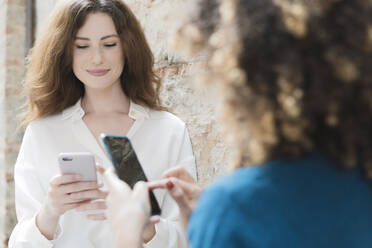 Two women using smartphones outdoors - FMOF00793