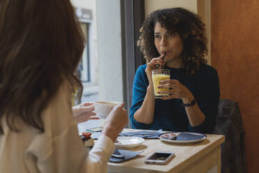 Zwei Frauen treffen und unterhalten sich in einem Café - FMOF00804
